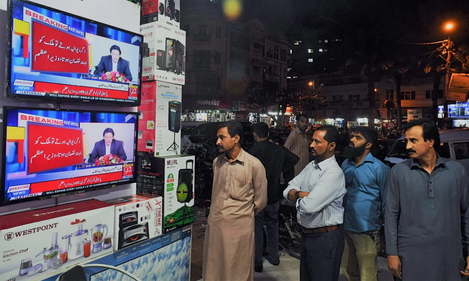 Pakistani residents watch the speech of Prime Minister Imran Khan as he addresses the nation after his visit to Saudi Arabia, at a electronic shop in Karachi on October 24, 2018. - Pakistani Prime Minister Imran Khan on October 24 said his government would seek a bail out from the International Monetary Fund (IMF) despite a $6 billion pledge from Saudi Arabia to to shore up a widening balance of payments crisis. (Photo by ASIF HASSAN / AFP)