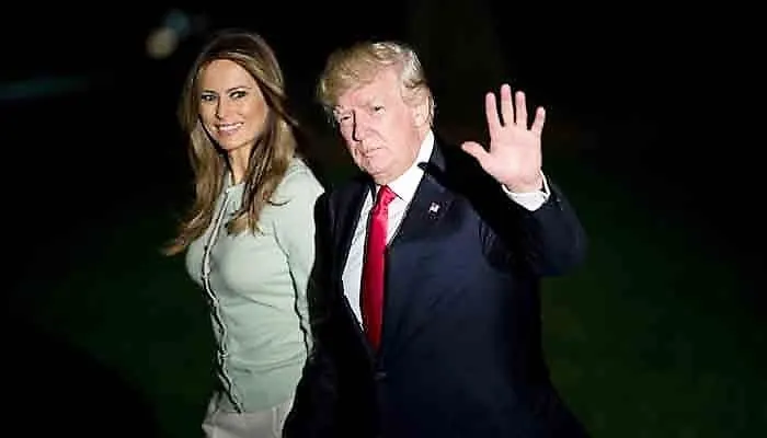 US President Donald Trump waves to the camera as First Lady Melania Trump smiles beside him.