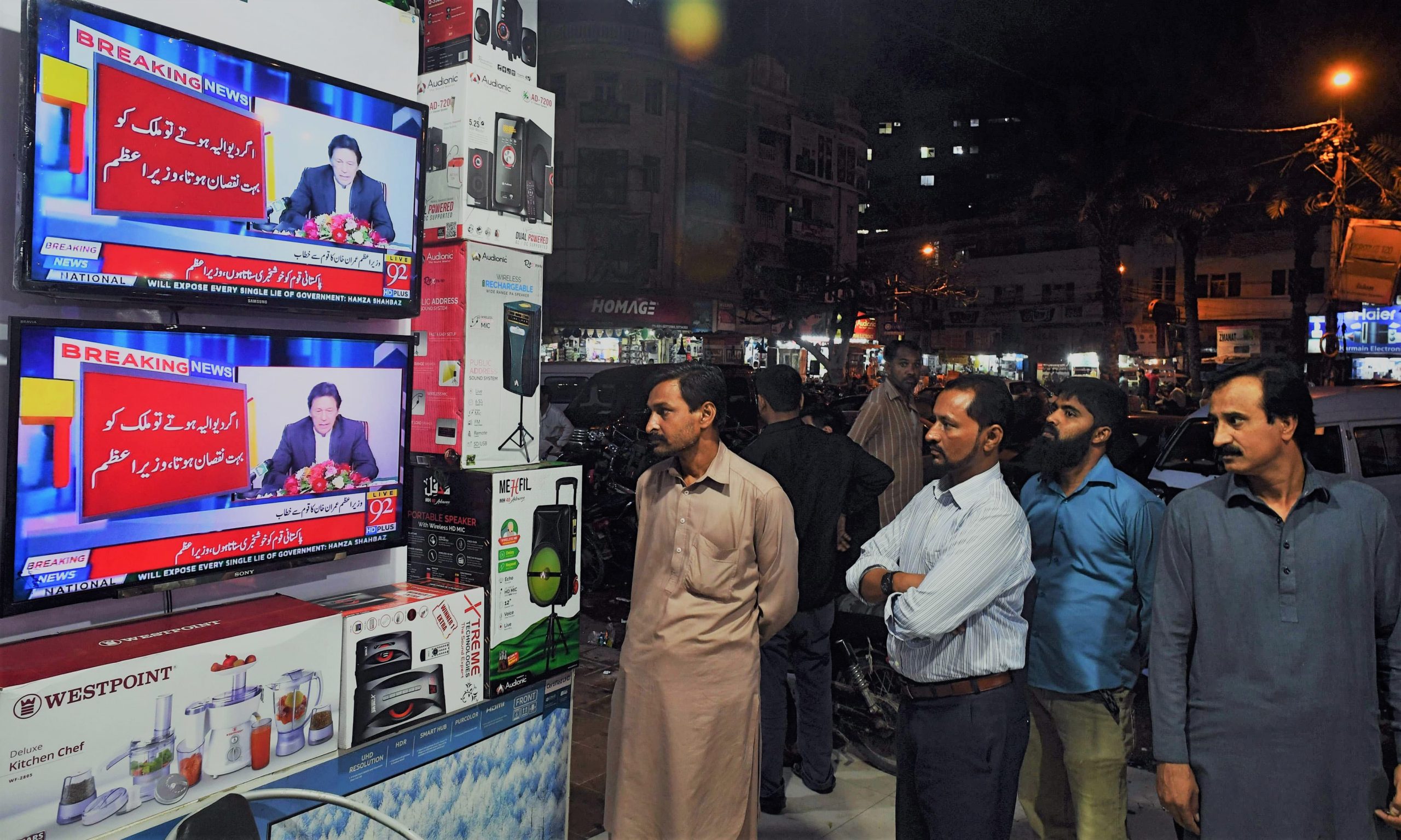 Pakistani residents watch the speech of Prime Minister Imran Khan as he addresses the nation after his visit to Saudi Arabia, at a electronic shop in Karachi on October 24, 2018. - Pakistani Prime Minister Imran Khan on October 24 said his government would seek a bail out from the International Monetary Fund (IMF) despite a $6 billion pledge from Saudi Arabia to to shore up a widening balance of payments crisis. (Photo by ASIF HASSAN / AFP)
